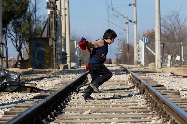 A refugee child sits on the railway near the border crossing bet