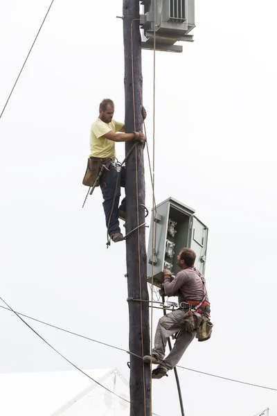 Workers climbing on Electrical concrete pole transmission line t