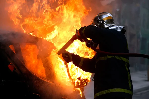 Firemen fighting a flaming car after an explosion