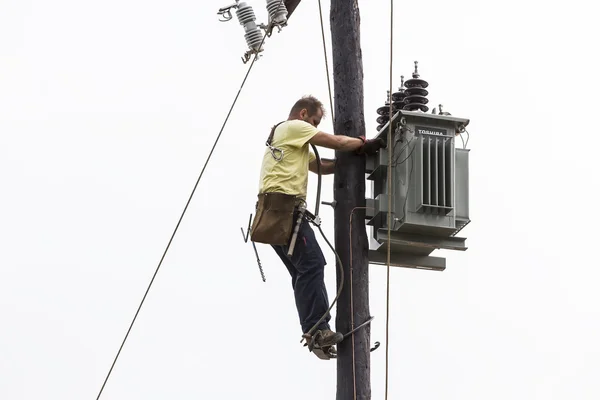 Worker climbing on Electrical concrete pole transmission line to