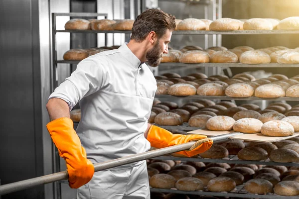 Baker putting with shovel bread loafs at the manufacturing