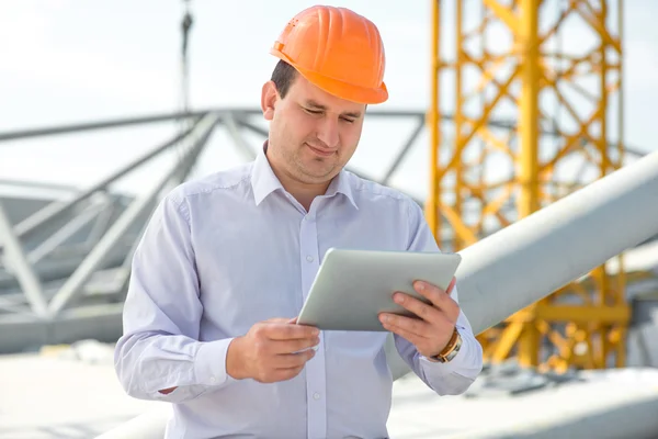 A foreman with digital tablet at the construction supervising the project.