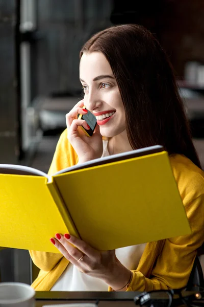 Woman with book and mobile phone