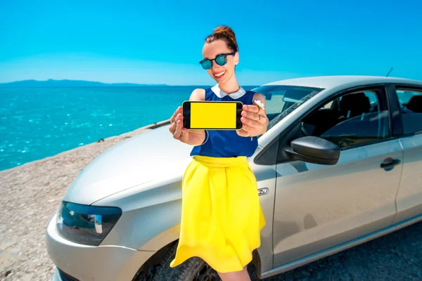 Woman showing phone screen near the car