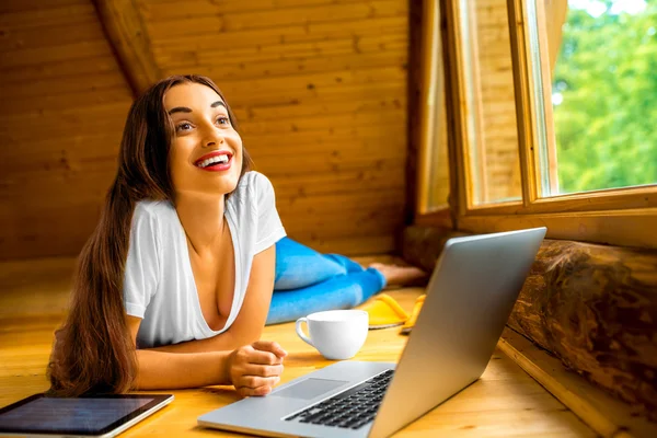 Woman with laptop in wooden house