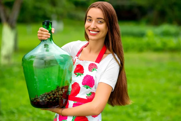 Woman holding big bottle with red berries in the garden