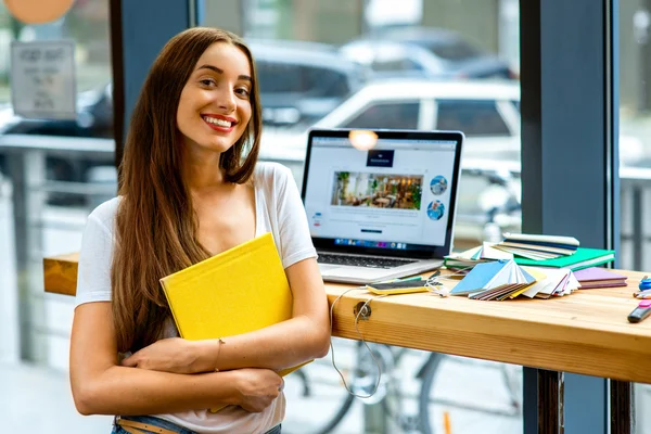 Young female student holding yellow book