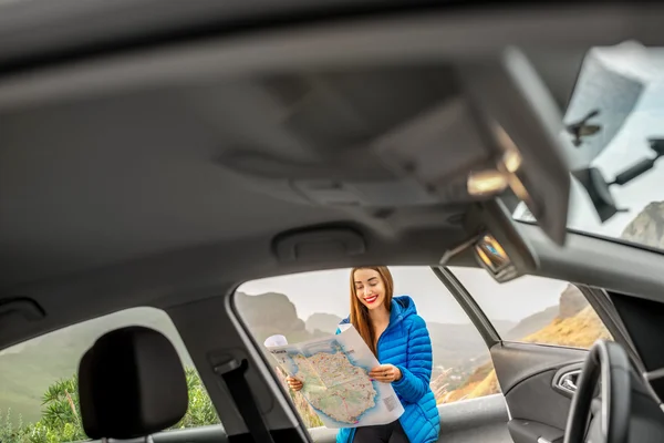 Female traveler with toursit map near the car