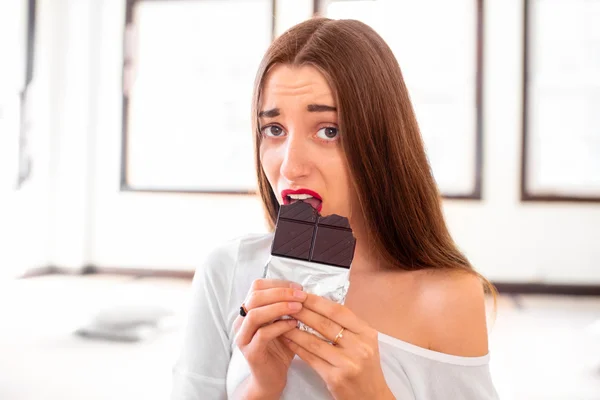 Woman with disappointed emotions holding chocolate