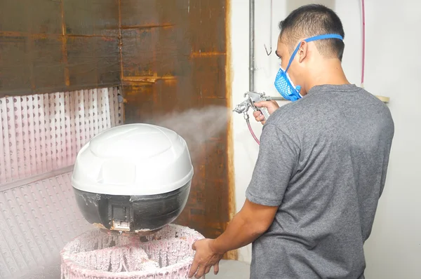 Worker painter wearing a protective mask painting a white color undercoat