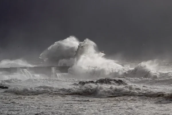 Stormy waves over old lighthouse and pier