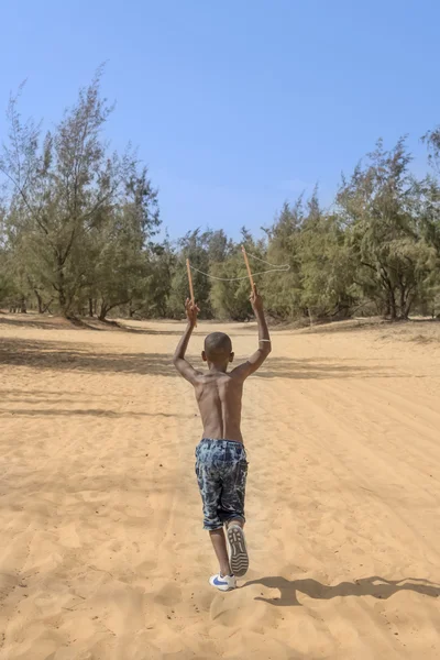 Afro boy running in the sand, ten years old