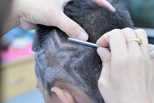 The boy's haircut with clipper and razor in the barber shop