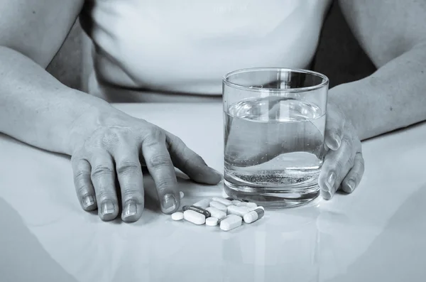 Hand with pill and glass of water
