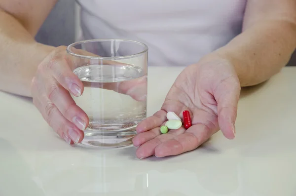 Hand with colorful pills and glass of water