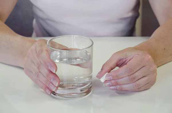 Hand with pill and glass of water