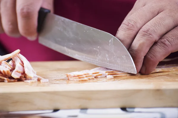 Closed up Chef cutting bacon with knife before cooking