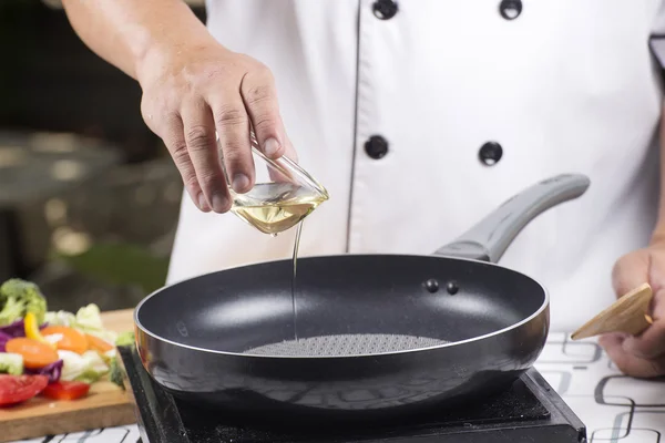 Chef pouring vegetable oil to the pan