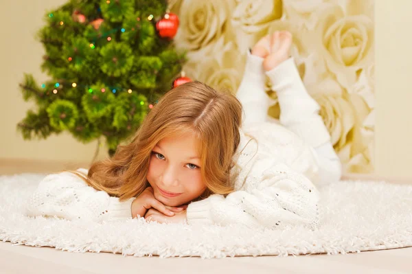 Girl lying on the carpet, looking at the camera and smiling.