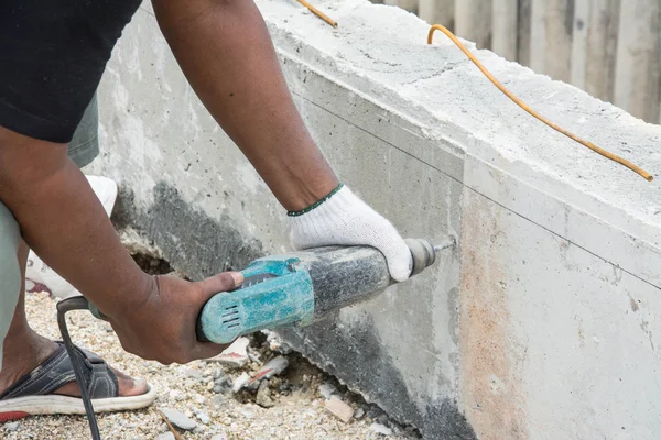 Man use eectric drill to drill the concrete beam