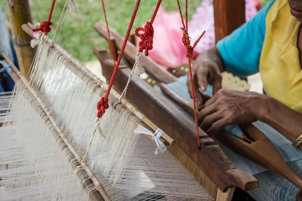 Woman weaving silk in traditional way at manual loom. Thailand