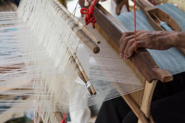 Woman weaving silk in traditional way at manual loom. Thailand