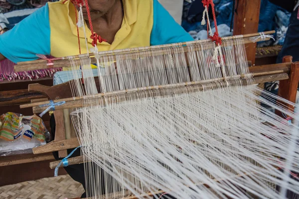 Woman weaving silk in traditional way at manual loom. Thailand