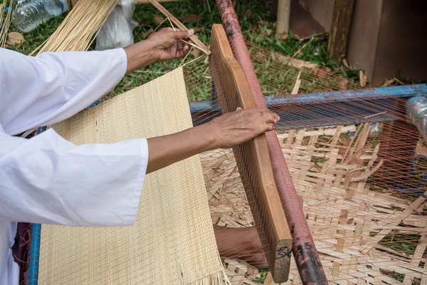 Woman weaving wicker in traditional way at manual loom. Thailand