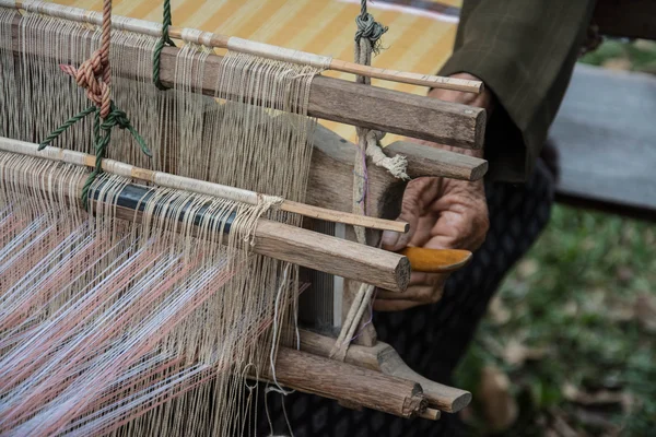 Woman weaving silk in traditional way at manual loom. Thailand