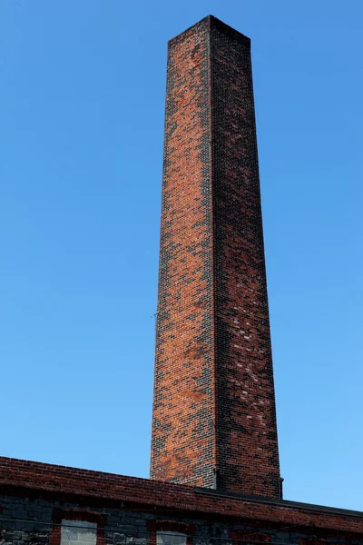 Square old Industrial chimney made from red bricks against the b