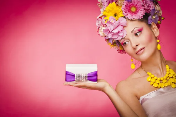 Young healthy woman holding gift box on her palm