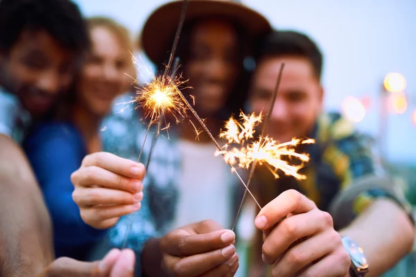 Multi-ethnic millenial group of friends folding sparklers