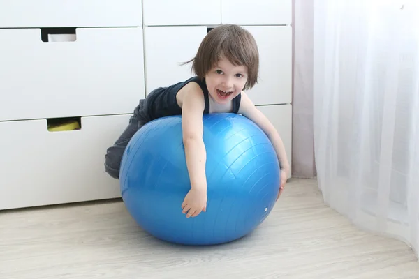Little boy (3 years) playing with a big blue ball at home