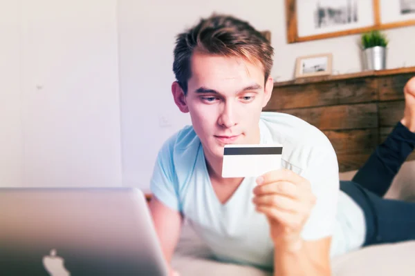 Young man holding a credit card during an e commerce payment. Vintage style.