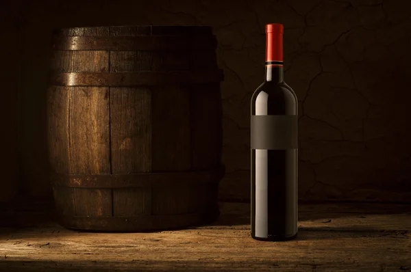 Still life with wine bottles, glasses and oak barrels.