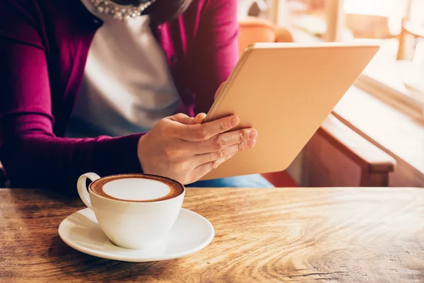 Woman using tablet computer in coffee shop with vintage tone.