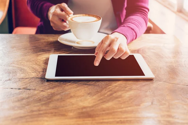 Hand woman touchscreen tablet computer and cup in coffee shop