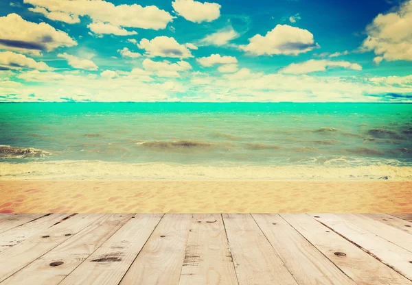 Wood table sand beach sea and in sky clouds with vintage tone.