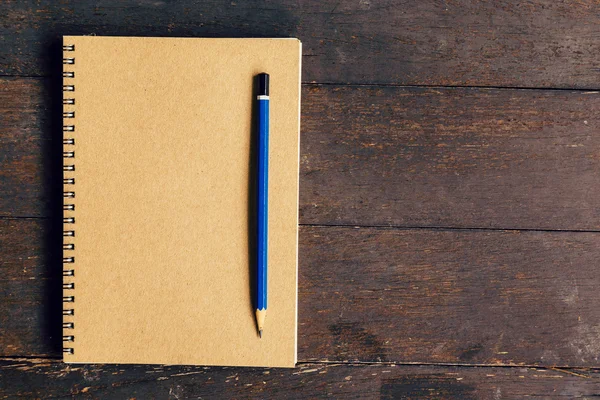 Brown book and pencil on wood table background with space