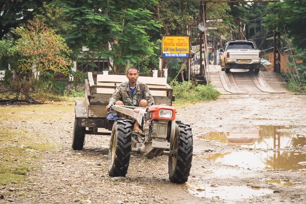 An unidentified man driving tractor on a rural road on oct 24, 2014, in Vang Vieng, Laos. Vang Vieng is a tourism-oriented town in Laos, lies on the Nam Song river.