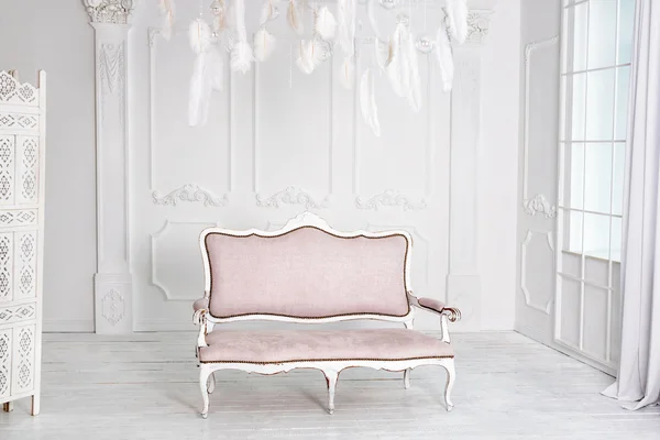 Classical white interior with pink sofa.