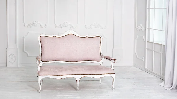 Classical white interior with pink sofa.