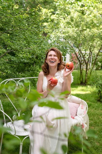 Pretty woman with box of apples havig fun in the summer garden. Outdoor celebration, tea party.