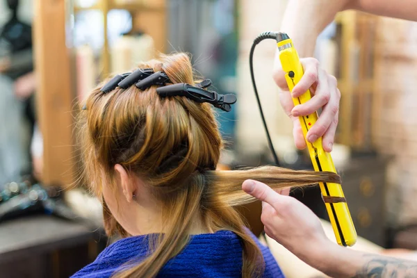 Professional hairdresser using curling iron hair curls