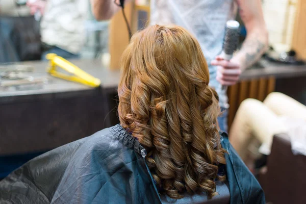Professional hairdresser using curling iron hair curls