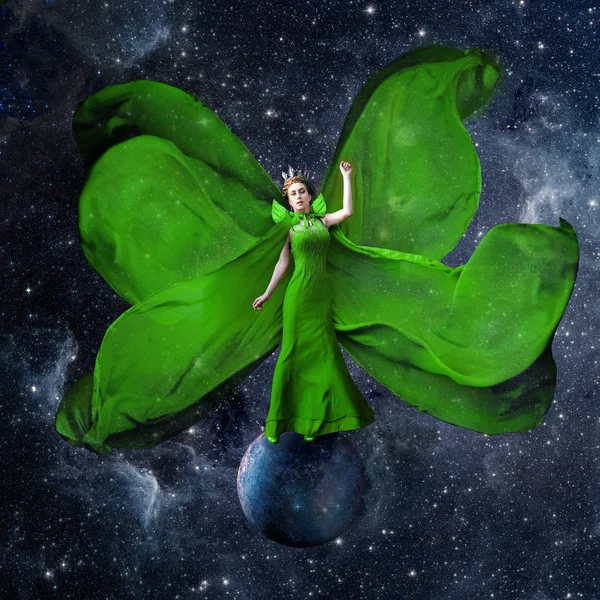 Green space queen. Beautiful woman in a fluttering dress standing and balancing on the planet in outer space. Fantastic art work. Elements of this image furnished by NASA.