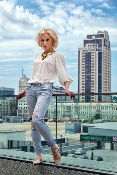 Outdoor summer fashion stunning portrait on pretty young blonde sexy woman dressed in a white shirt and torn jeans having fun in the street