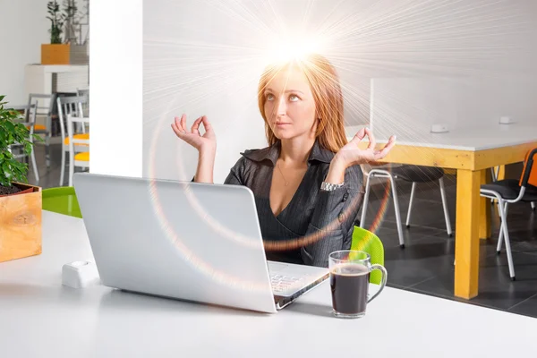 Business woman meditating near laptop. Relaxed office worker doing yoga meditation during a coffee break. Green eco healthy office concept.