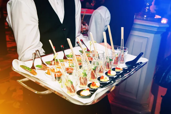 Server holding a tray of appetizers at banquet. Toned image