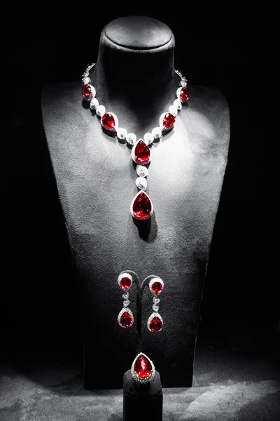 Set of luxury jewelry made of white gold with diamonds and rubies on a stand.